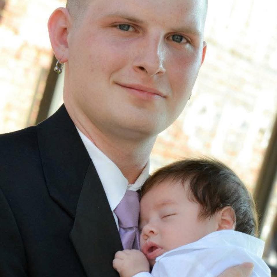 Joshua holding his son as a newborn